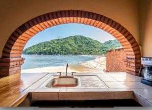 a kitchen with an archway with a view of a beach at Casa Frente al mar in Yelapa