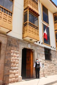 un hombre parado frente a un edificio con una bandera en Fuente de Agua Hotel, en Cusco