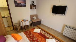 Pokój z telewizorem, łóżkiem i stołem w obiekcie Apartment Kreslin w mieście Vantačići