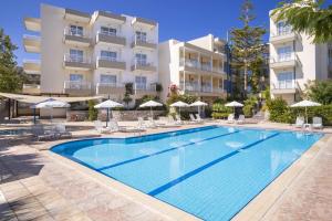 une piscine avec chaises et parasols devant un immeuble dans l'établissement Ibiscos Garden Hotel, à Réthymnon