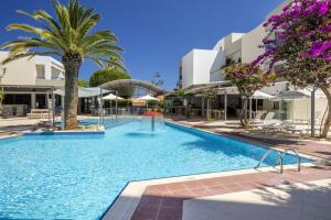 a large swimming pool with palm trees and buildings at Ibiscos Garden Hotel in Rethymno