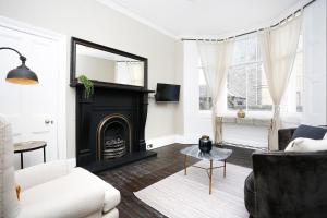 uma sala de estar com uma lareira a preto e mobiliário branco em ALTIDO Modern 1-BR Apartment in Trendy Stockbridge em Edimburgo