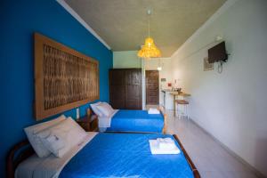 a bedroom with two beds and a blue wall at Villa Spyridoula studios on the Beach in Sidari