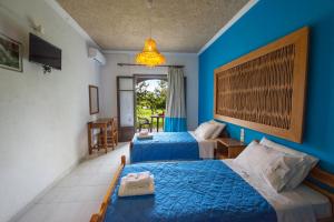 two beds in a room with blue walls at Villa Spyridoula studios on the Beach in Sidari