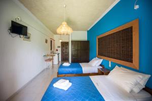 a bedroom with two beds and a blue wall at Villa Spyridoula studios on the Beach in Sidari