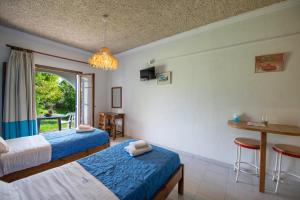 a bedroom with two beds and a table and a window at Villa Spyridoula studios on the Beach in Sidari