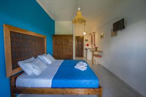 a bedroom with a bed with blue sheets and a kitchen at Villa Spyridoula studios on the Beach in Sidari