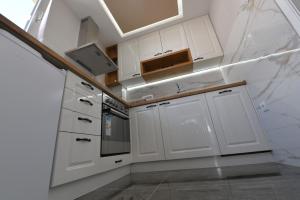 a white kitchen with white cabinets and a sink at Family apartman Bijeljina in Bijeljina