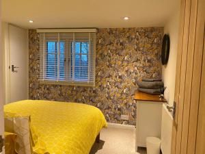 a bedroom with a bed with a yellow comforter at Cosy and Contemporary Cottage in Uckfield
