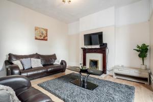a living room with a leather couch and a fireplace at Spacious 5 Bedroom House in Gravesend in Gravesend