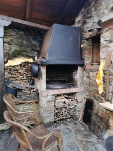 una chimenea de piedra con 2 sillas frente a ella en Habitación Cuadruple con derecho a Barbacoa y patio, en Navia de Suarna