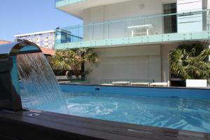 a swimming pool with a water feature in front of a building at Appartamenti Fiore in Lignano Sabbiadoro