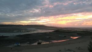 einen Sonnenuntergang über einem Strand mit Booten im Sand in der Unterkunft 酵法自然環保民宿 in Houlong