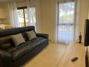 a living room with a black leather couch and a wooden table at LANZAROTE VACACIONAL in Arrecife