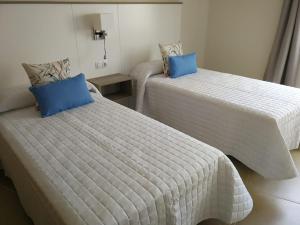 2 Betten in einem kleinen Zimmer mit blauen Kissen in der Unterkunft LANZAROTE VACACIONAL in Arrecife