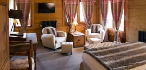 a bedroom with a bed and chairs and a television at Chalet-Hôtel Les Cimes in Le Grand-Bornand