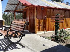 Cabañas La Campiña Ubalá في Ubalá: كرسي جلوس امام مبنى خشبي