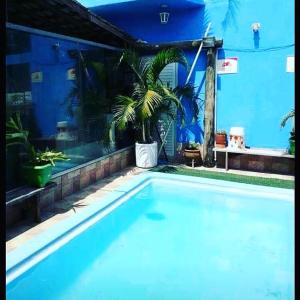 uma grande piscina em frente a um edifício azul em The House Pousada e Hospedagem Enseada- Guarujá no Guarujá