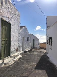 eine Gasse mit weißen Gebäuden und einer grünen Tür in der Unterkunft CASA ABUELA MINA in Lomo de Arico