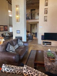 un salon avec un canapé en cuir et une télévision dans l'établissement Luna rossa 19 Zebula golf course and spa resort, à Mabula