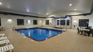 a large swimming pool in a room with a table and chairs at Estherville Hotel & Suites in Estherville