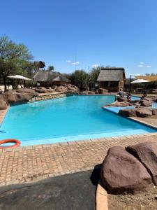 une grande piscine d'eau bleue et de rochers dans l'établissement Luna rossa 19 Zebula golf course and spa resort, à Mabula