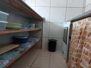 una cocina con una estantería con platos y un cubo de basura en Residencia Siqueira, en Garopaba
