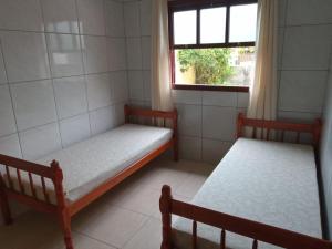 2 camas en una habitación pequeña con ventana en Residencia Siqueira, en Garopaba