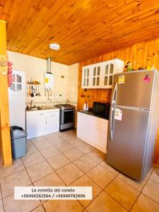 uma cozinha com um frigorífico em aço inoxidável e tectos em madeira em La Estrella del canelo em Algarrobo