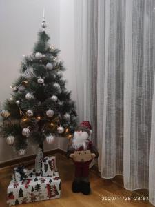 une clause de santa à côté d'un arbre de Noël dans l'établissement Apartman Pahulja, à Zlatibor