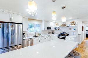 a kitchen with white cabinets and stainless steel appliances at The Chinook House in Depoe Bay +27 photos
