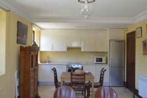 una cocina con armarios blancos y una mesa con sillas. en Apartamento Casona de la Viesca, en Liendo