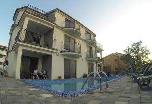 a building with a swimming pool in front of a building at Apartmani Zaric in Malinska