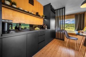 a kitchen with black cabinets and a table with a chair at Kutica in Nová Baňa