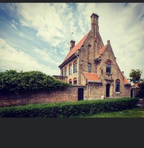 an old brick building with a tower on top of it at The westhouse in Middelkerke