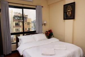 una camera da letto con un letto con lenzuola bianche e una finestra di Hotel Buddha Land a Kathmandu