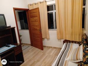 a bedroom with a bed and a tv and windows at Beco das Flores in Carrancas