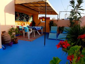 een terras met een tafel en stoelen op een blauwe vloer bij Dar Khadija in Asilah