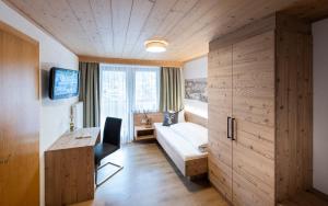 Habitación de hotel con cama, escritorio y ventana en Ferienhof Schöne Aussicht, en Pfunds