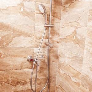 La salle de bains est pourvue d'une douche et d'un mur en pierre. dans l'établissement Home sweet home, à Radviliškis