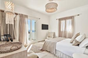 a white bedroom with a bed and a couch at Volcano Luxury Suites Milos - Adults Only in Paliochori