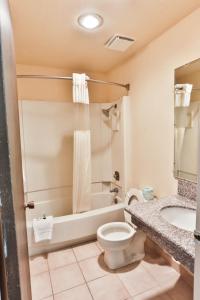 Country Inn Beaver Utah في بيفر: حمام مع مرحاض وحوض استحمام ومغسلة