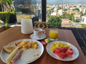 a table with two plates of breakfast food and a glass of orange juice at Cavalta by Bernalo Hotels in Medellín
