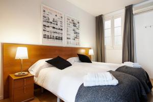 1 dormitorio con 2 camas y mesa con lámpara en Habitat Apartments Plaza España, en Barcelona