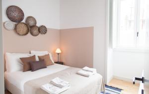 ein Schlafzimmer mit einem weißen Bett und Handtüchern darauf in der Unterkunft FLH Intendente Charming Flat in Lissabon
