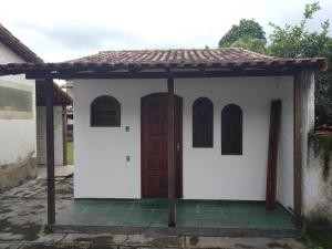 a small white house with a brown door at Flat Maricá II in Maricá