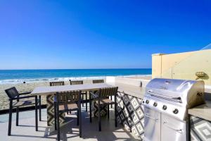 a grill and a table and chairs on the beach at Ocean Villas Beach Front in Carlsbad
