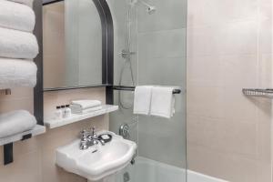 a white bathroom with a sink and a shower at voco The Franklin New York, an IHG Hotel in New York