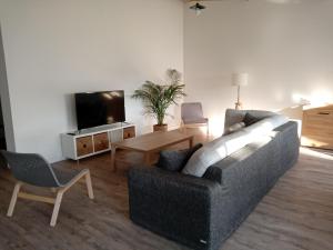 sala de estar con sofá, mesa y TV en Chambres d'étape - Le Répit de l'Oust - Certifié Ecolabel Européen, en Peillac