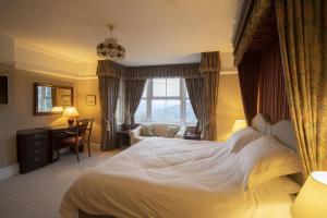 チェルトナムにあるクリーブ ヒル ホテルの大きなベッドとデスクが備わるホテルルームです。